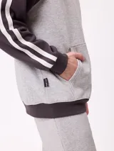 Canguro con capucha de estilo deportivo, con cuerpo en color celeste y mangas raglán en color negro. Presenta el logo de la marca estampado en el pecho, bolsillo tipo canguro frontal y franjas blancas laterales en las mangas.