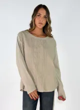 Blusa de manga larga en color blanco, con cuello redondo y detalle de alforzas verticales en el frente. Presenta un corte holgado y fluido.