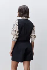 Short de tiro alto confeccionado en algodón, con calce relajado y silueta recta. Presenta pinzas delanteras, bolsillos laterales y botones decorativos en la cintura.