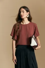 Top de color azul, con escote redondo a la base y mangas cortas amplias con caída fluida. Presenta una silueta relajada y un diseño minimalista.