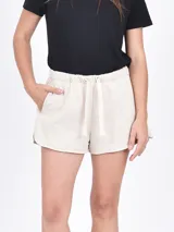 Short de algodón negro con cintura elástica, cordón ajustable y bolsillos laterales. Presenta un corte holgado con aberturas laterales redondeadas.