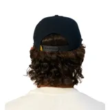 Gorra de visera plana color negro, con parche circular bordado en el frente que presenta un diseño gráfico con texto y una flor central.