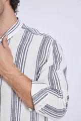 Camisa de corte regular con diseño de rayas verticales finas en tonos claros, cuello clásico y mangas largas con puños abotonados.