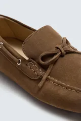 Mocasín casual de cuero color marrón claro con acabado serraje, horma redonda, detalle de lazo en el empeine y suela de goma.