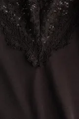 Top de breteles finos con escote en V y bajo asimétrico, ambos decorados con ribetes de encaje. Confeccionado en tejido de punto suave.