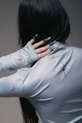 Minivestido negro con cuello alto y mangas largas. Presenta un drapeado lateral con lazos ajustables y un estampado de rosa en el frente.