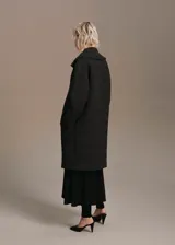 Abrigo largo estilo oversize con diseño de cuadros, cuello con solapa de muesca, cierre delantero con botones y bolsillos laterales.