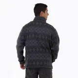 Campera polar con cierre frontal completo, confeccionada en tejido exterior tipo punto con estampado geométrico en tonos oscuros. Cuenta con cuello alto, bolsillos laterales y un bolsillo vertical en el pecho con cierre, además de un parche con el logo de la marca.