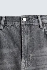 Pantalón de jeans de algodón, color gris oscuro con efecto lavado. De tiro medio y corte relajado con pierna recta desde la cadera hasta el tobillo. Presenta cinco bolsillos y cierre frontal con botonadura.