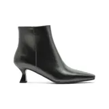 Bota corta de vestir color negro, con punta cuadrada y taco bajo tipo kitten heel. Presenta un diseño minimalista con cierre lateral interno.