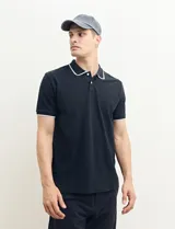Remera polo azul marino con ribetes blancos en el cuello y en los bordes de las mangas corta, y cierre frontal de botones.