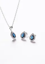 Aros tipo caravanas con diseño de gota, elaborados en plata 925 con una piedra central de zirconia azul rodeada por pequeñas zirconias blancas.