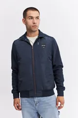 Campera de estilo deportivo con cierre frontal, confeccionada en una combinación de nylon y algodón. Presenta un diseño con paneles texturizados en las mangas, cuello alto y un parche decorativo con coordenadas en el pecho.