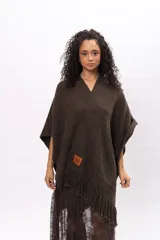 Ruana de tejido de punto color marrón chocolate, con diseño envolvente, cuello en V y detalle de flecos en el ruedo. Incluye etiqueta de cuero sintético con el logo de la marca en la parte frontal.