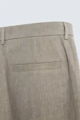 Pantalón de corte straight relaxed fit confeccionado en tejido de lino con efecto lavado. Presenta cierre frontal con cremallera y botón, bolsillos laterales y bolsillos traseros de vivo.