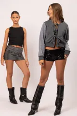 Musculosa negra entallada con cuello redondo, decorada con apliques metálicos de tachas, estrellas y ojalillos en el contorno del cuello y las sisas.