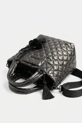 Cartera tote negra de diseño matelasse acolchado, con doble asa de mano y correa larga ajustable con inscripciones. Cuenta con cierre superior y detalle de llavero con borla colgante.