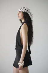 Vestido corto negro de algodón con cuello halter y faja en la cintura que se ata detrás del cuello.