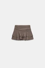 Falda pantalón de tiro medio con diseño de volantes en el ruedo y detalle de pliegues en la cintura. Cuenta con cierre lateral con cremallera.