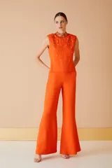 Blusa naranja sin mangas con cuello alto y apliques de lentejuelas y cuentas en el cuello y el cuerpo.