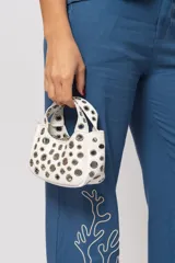Cartera blanca pequeña con doble asa corta y tachas plateadas.