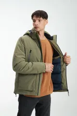 Campera verde militar con capucha, cierre frontal con cremallera y bolsillos laterales con solapa. Interior acolchado en color azul marino.