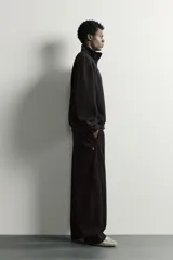 Pantalón jogger de corte relajado en color negro, confeccionado en tejido con elasticidad. Presenta cintura elástica con cordón ajustable y bolsillos laterales decorados con tachas metálicas.