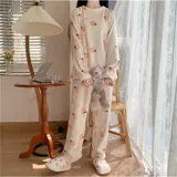 Conjunto de pijama de dos piezas confeccionado en plush suave, compuesto por una remera de manga larga y pantalón largo. Presenta un diseño estampado de duraznos sobre fondo color crema.