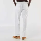 Pantalón de lino blanco de corte recto con cintura elástica y cordón ajustable.