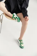 Zapatillas bajas de cuero sintético color crema con detalles en verde pastel y suela celeste.