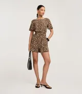 Enterito corto de mangas cortas con estampado de leopardo. Presenta cuello redondo con cierre tipo gota en la espalda, elástico en la cintura y lazo ajustable a juego.