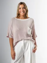 Remera tejida color crema con cuello redondo y bolsillo frontal verde.