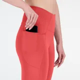 Calza deportiva capri color coral, de tiro alto, con bolsillos laterales y logo reflectivo en la pierna.