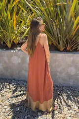 Vestido largo color ladrillo, de breteles finos y corte holgado. Presenta un panel inferior color beige.