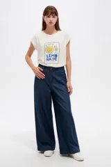 Remera de algodón blanca de manga corta y cuello redondo, con diseño holgado y estampado frontal con la inscripción 'Lemonade' acompañada de ilustraciones de limones y una jarra.