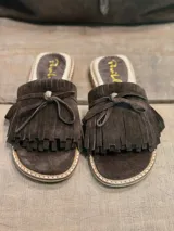 Sandalias bajas color marrón chocolate, con base beige y detalle de flecos y lazo en la capellada.
