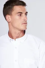 Camisa blanca de tela oxford con manga larga y logo bordado en el bolsillo. Cuello con botones y tablón central en la espalda.