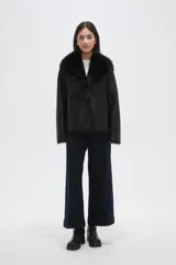 Chaqueta de eco-cuero negro con interior y cuello de piel sintética, diseño holgado, manga larga y cierre frontal con un botón.