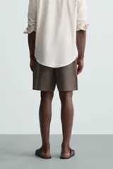 Bermuda de lino color blanco hueso, de corte relajado y tiro medio. Presenta cintura elástica ajustable con cordón, pliegues frontales y bolsillos laterales y trasero.