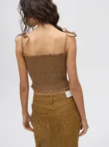 Top corto de tela fruncida color celeste, con tirantes finos que se atan en los hombros.