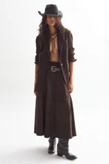 Falda midi de gamuza color marrón, con diseño de corte amplio, tajo lateral y cintura con elástico en la parte trasera. Cuenta con cierre metálico lateral y forro interior.