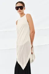 Top color beige con cuello redondo, manga sisa y bajo asimétrico. Confeccionado en hilatura de lyocell con efecto doble.