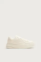 Zapatilla deportiva de diseño monocolor en tono crema, con cordones al tono y suela de plataforma con volumen.