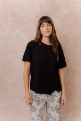 Remera negra de manga corta, con cuello redondo, calce relajado, recortes curvos en el frente y terminación inferior asimétrica con cintura ancha.