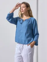 Blusa celeste de lyocell con cuello a la base y escote en V con lazo de ajuste. Manga larga amplia.