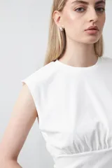 Top sin mangas de tejido acanalado color blanco, con cuello redondo, hombros definidos y detalle de frunce bajo el busto que aporta estructura.