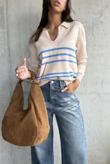 Sweater de punto fino color beige, con cuello polo y escote en V. Presenta tres rayas horizontales azules en el pecho y mangas largas con puños acanalados.