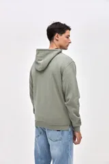 Canguro de felpa con friza, diseño con cortes en el cuerpo y bolsillos laterales integrados. Presenta capucha, puños elásticos y un pequeño detalle bordado en la manga.