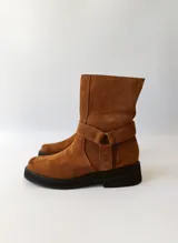 Bota corta de cuero color camel, con correa decorativa alrededor del tobillo y suela de goma negra.