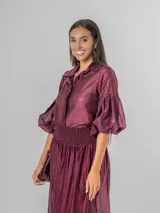 Camisa de organdí de algodón italiano en color bordó, con cuello camisero, cierre frontal con botones y mangas farol que aportan volumen.